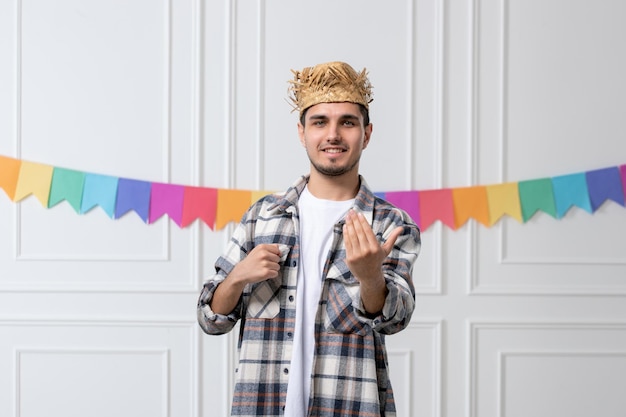 Festa junina chico guapo con camisa a cuadros en sombrero de paja celebrando el festival invitando a alguien