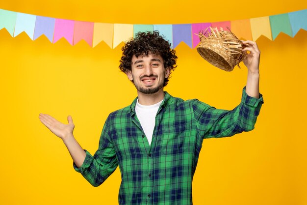 Festa junina chico lindo joven quitándose el sombrero de paja y coloridas banderas festival brasileño