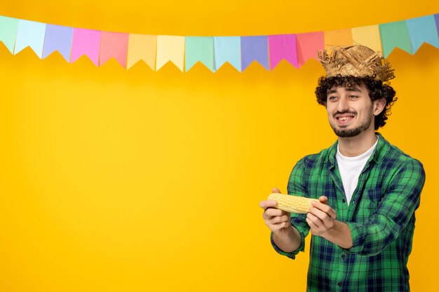 Festa junina chico lindo joven con sombrero de paja y banderas coloridas festival brasileño dando maíz