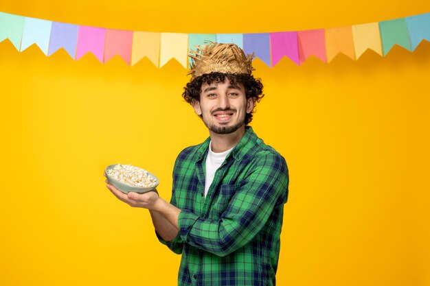 Festa junina chico lindo joven con sombrero de paja y banderas coloridas festival brasileño con palomitas de maíz