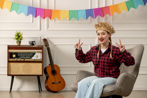 Festa junina linda chica con sombrero de paja verano brasileño con guitarra de radio retro que muestra el signo de la paz