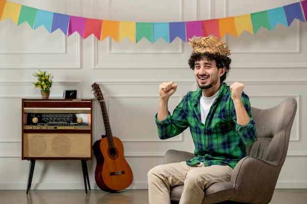 Festa junina lindo joven con sombrero de paja con radio retro y banderas coloridas emocionado