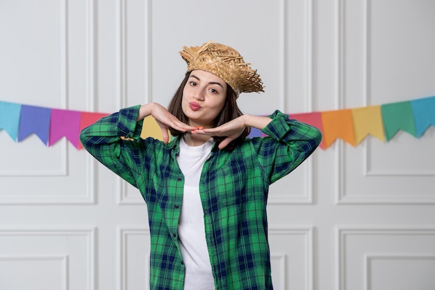 Festa junina niña bonita con sombrero de paja celebrando la fiesta brasileña haciendo cara de beso