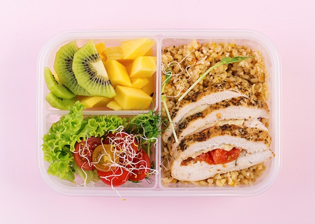 Fiambrera de pollo, bulgur, microgreens, tomate y fruta. Comida saludable y saludable. Para llevar. Caja de almuerzo. Vista superior