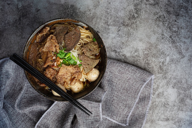 Fideos de carne de cerdo, comida clásica tailandesa y menús populares y sopas listas para comer. También hay una albahaca en el tazón.