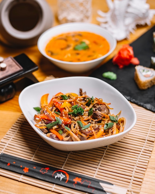 Foto gratuita fideos con carne pimiento cebolla cebolla sésamo vista lateral