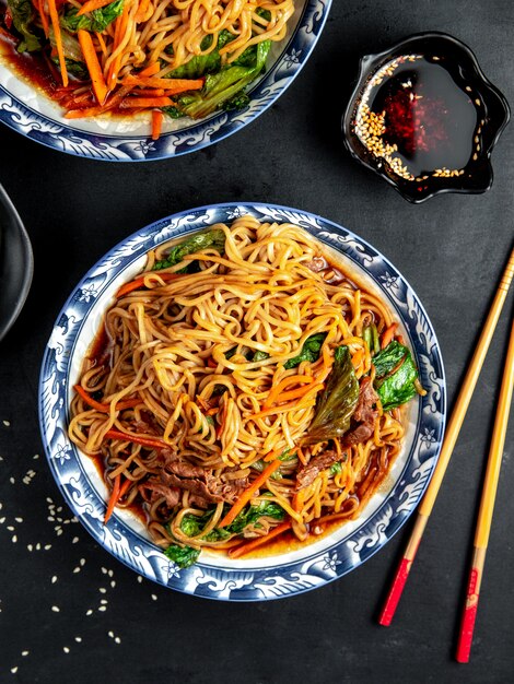 fideos con carne y verduras en la mesa negra