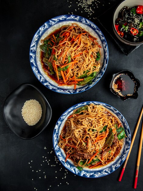 fideos con carne y verduras en la mesa negra