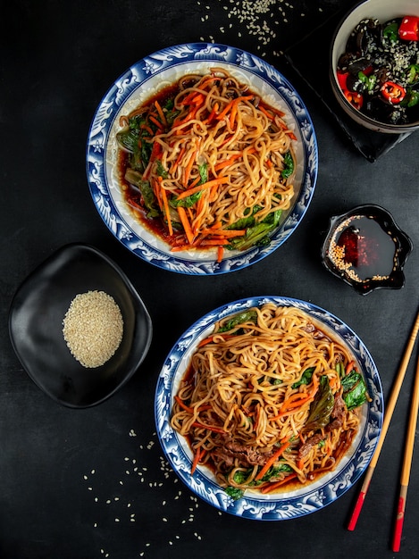 fideos con carne y verduras en la mesa negra