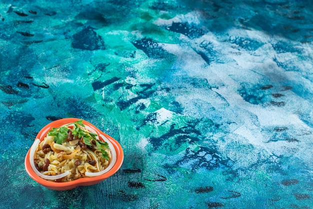 Fideos caseros con frijoles en un cuenco, sobre la mesa azul.