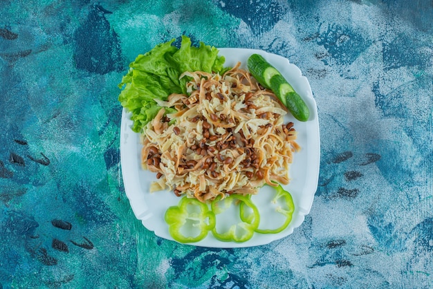 Fideos caseros con rodaja de pimienta en un plato, sobre la mesa azul.