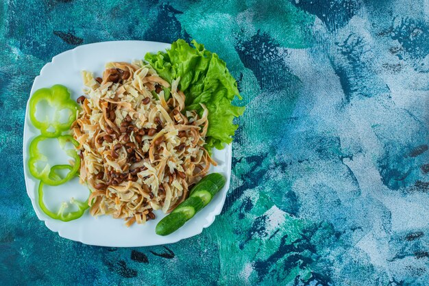 Fideos caseros con rodaja de pimienta en un plato, sobre la mesa azul.