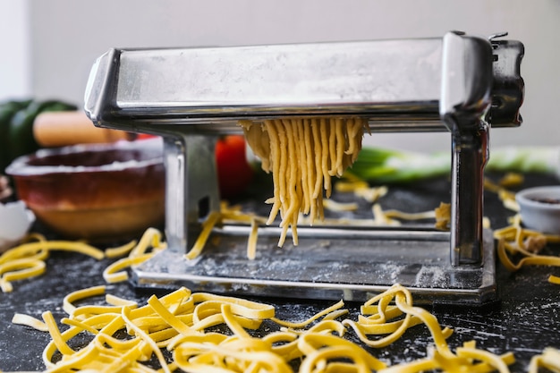 Foto gratuita fideos sin cocinar y máquina de pasta