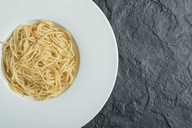 Fideos deliciosos en un plato blanco sobre negro.