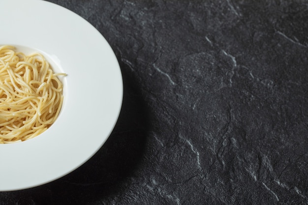 Fideos deliciosos en un plato blanco sobre negro.