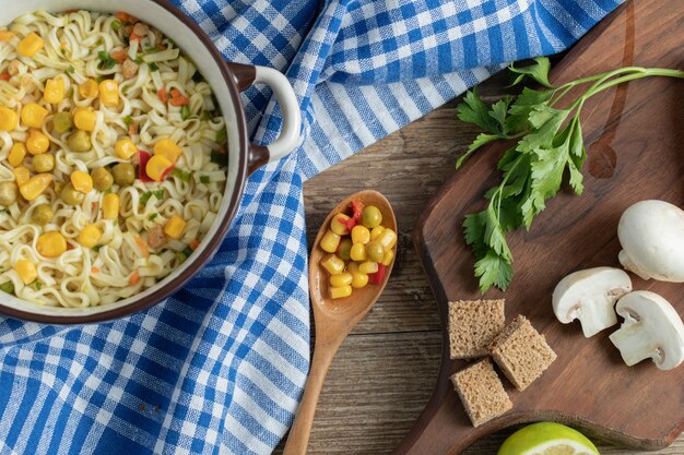 Fideos hervidos con guisantes y callos y verduras frescas sobre tabla de madera