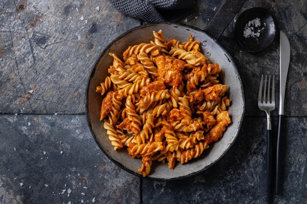 Fideos macarrones con carne y salsa de tomate servidos en sartén sobre la mesa.