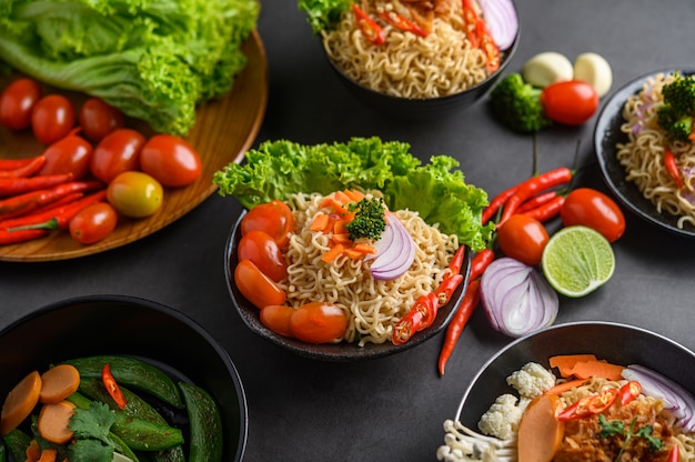 Fideos picantes en el bol con ingredientes sobre superficie de cemento negro