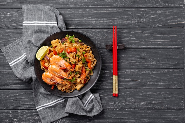 Fideos planos con verduras y pollo con palillos