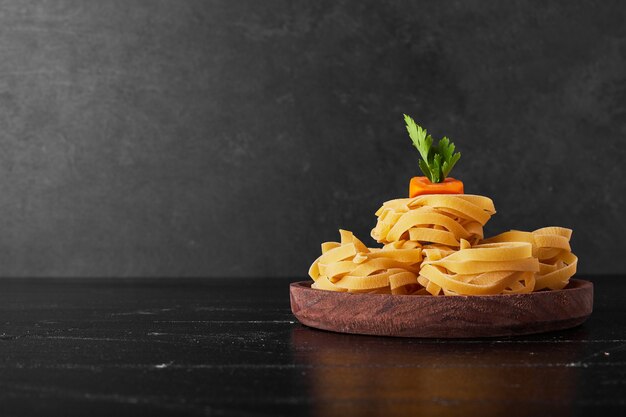 Fideos en un plato de madera con verduras