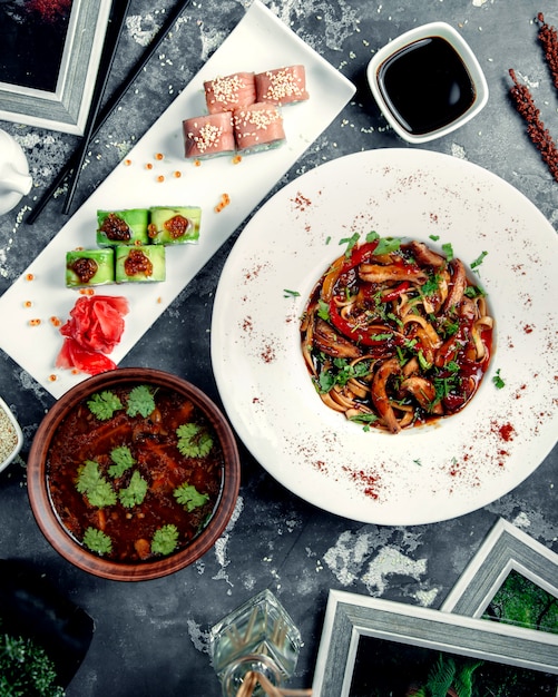 Fideos de pollo en la mesa con rollos de sushi