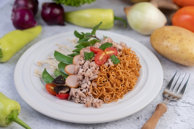 Fideos salteados con carne picada de cerdo, edamame, tomates y champiñones en un plato blanco.