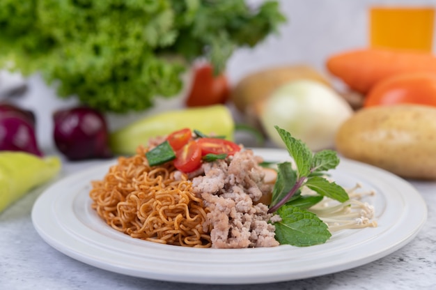 Fideos salteados con carne picada de cerdo, edamame, tomates y champiñones en un plato blanco.