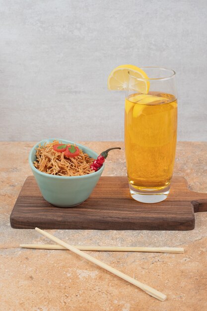 Foto gratuita fideos con tomate y vaso de jugo sobre plancha de madera. foto de alta calidad