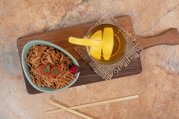 Fideos con tomate y vaso de jugo sobre tabla de madera