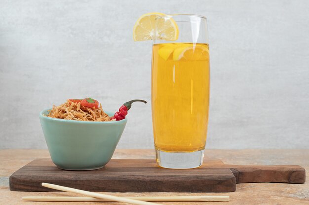 Fideos con tomate y vaso de jugo sobre tabla de madera