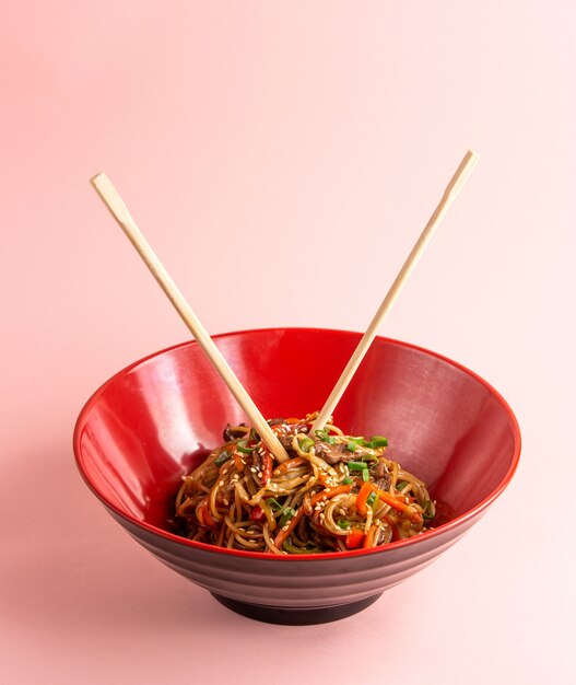 fideos udon con carne pimiento zanahoria cebolla tierna salsa de soja y sésamo en un tazón