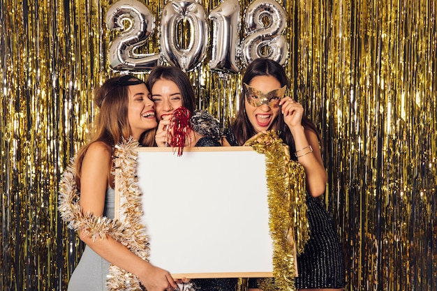 Foto gratuita fiesta de año nuevo con chicas sujetando pizarra blanca