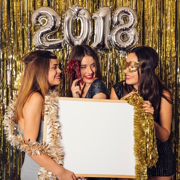 Fiesta de año nuevo con chicas sujetando pizarra