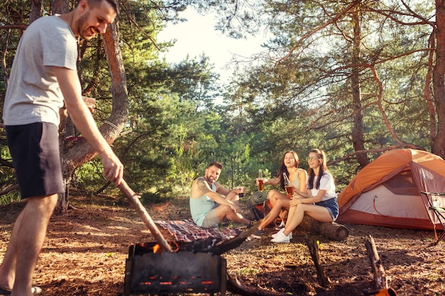 Fiesta, campamento de grupo de hombres y mujeres en el bosque. vacaciones, verano, aventura, estilo de vida, concepto de picnic