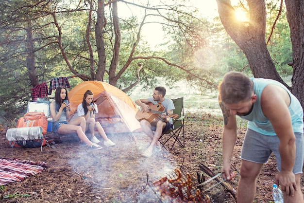 Fiesta, campamento de grupo de hombres y mujeres en el bosque.