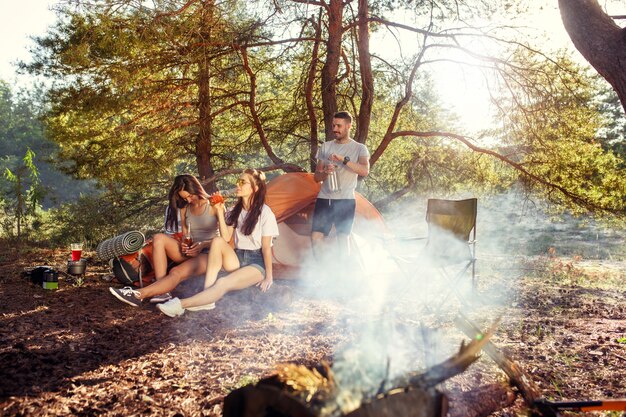 Fiesta, campamento de hombres y mujeres en el bosque. Se relajan