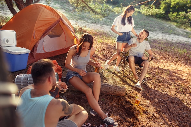 Fiesta, campamento de hombres y mujeres en el bosque. Se relajan