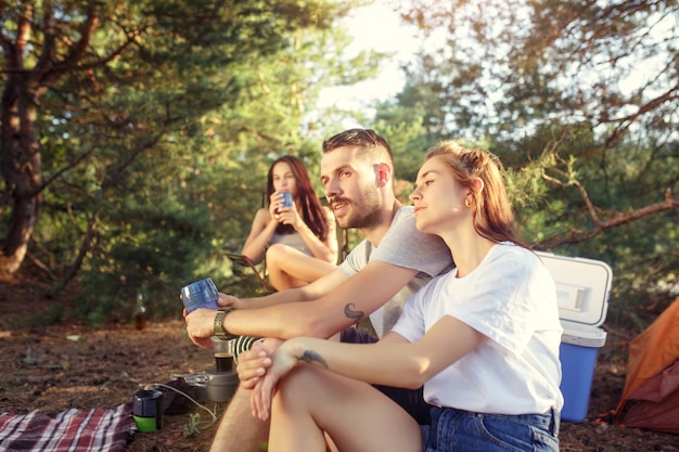 Fiesta, campamento de hombres y mujeres en el bosque. Se relajan