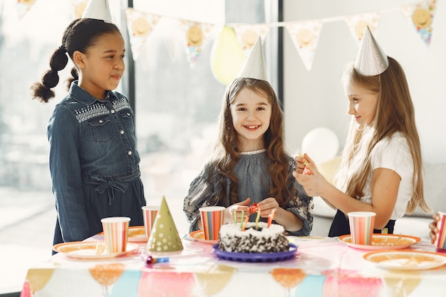 Fiesta de cumpleaños divertida para niños en habitación decorada. Niños felices con pastel y globos.