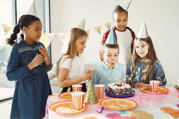Fiesta de cumpleaños divertida para niños en habitación decorada. Niños felices con pastel y globos.