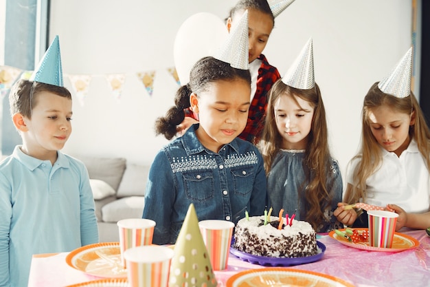 Fiesta de cumpleaños divertida para niños en habitación decorada. Niños felices con pastel y globos.