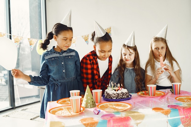 Fiesta de cumpleaños divertida para niños en habitación decorada. Niños felices con pastel y globos.