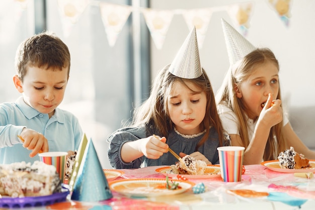 Fiesta de cumpleaños divertida para niños en habitación decorada. Niños felices con pastel y globos.