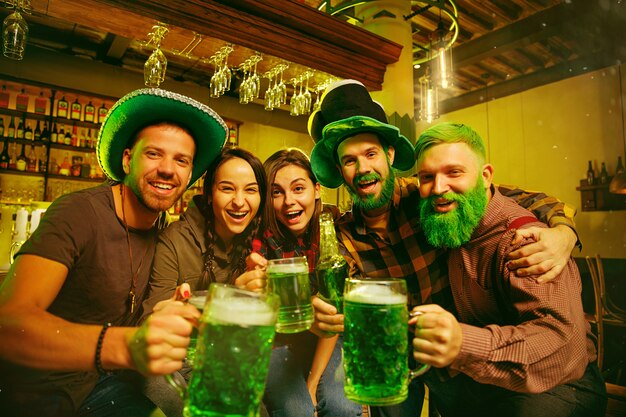 Fiesta del día de San Patricio. Amigos felices está celebrando y bebiendo cerveza verde.