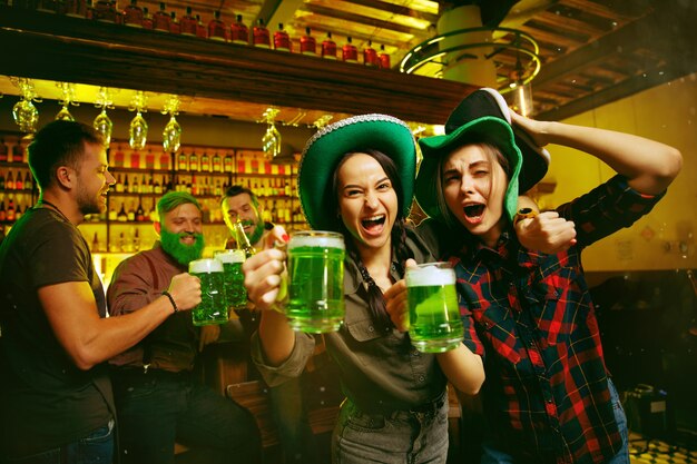 Fiesta del día de San Patricio. Amigos felices está celebrando y bebiendo cerveza verde.