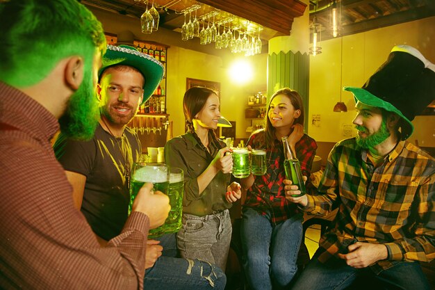 Fiesta del día de San Patricio. Amigos felices están celebrando y bebiendo cerveza verde.