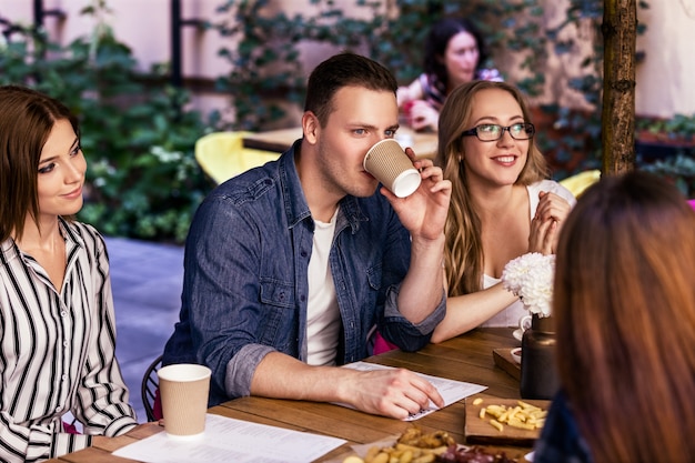 Fiesta informal y amigable con compañeros de trabajo en el acogedor café con refrigerios deliciosos en un cálido día de verano