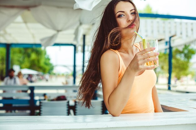 Fiesta de verano de estilo de vida. Mujer joven sexy con el pelo largo bebiendo cócteles en el bar de la playa.