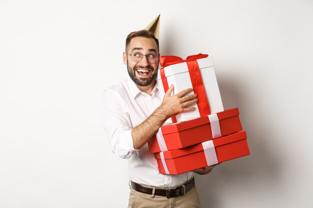 Fiestas y celebraciones. Hombre emocionado tener fiesta de cumpleaños y recibir regalos, mirando feliz, de pie