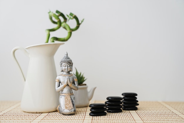 Figura de buda en frente de planta de bambú y piedras volcánicas